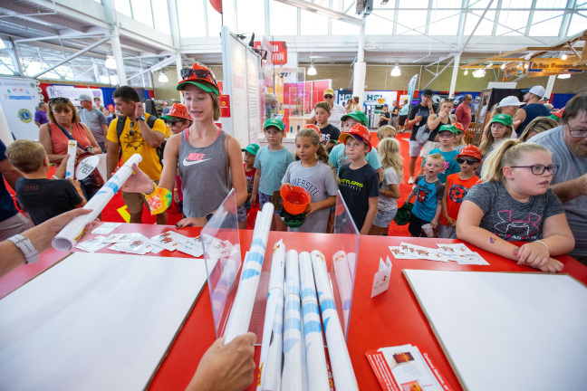 Visitors picking up posters at the ISU exhibit at the Iowa State Fair