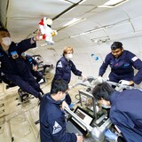 A photograph showing researchers working with their 3D printer during a NASA microgravity flight.